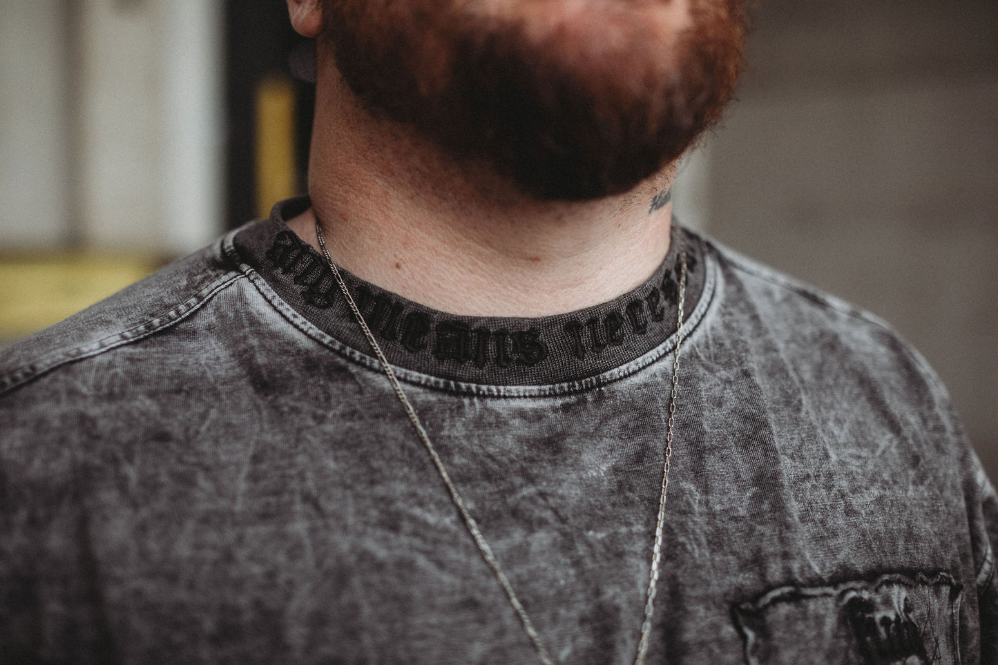 Close-up of a person wearing a gray shirt with a blurred background