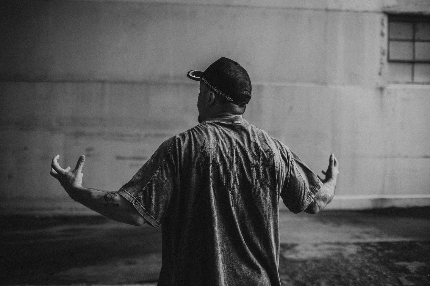 Person standing with arms outstretched in front of a plain wall