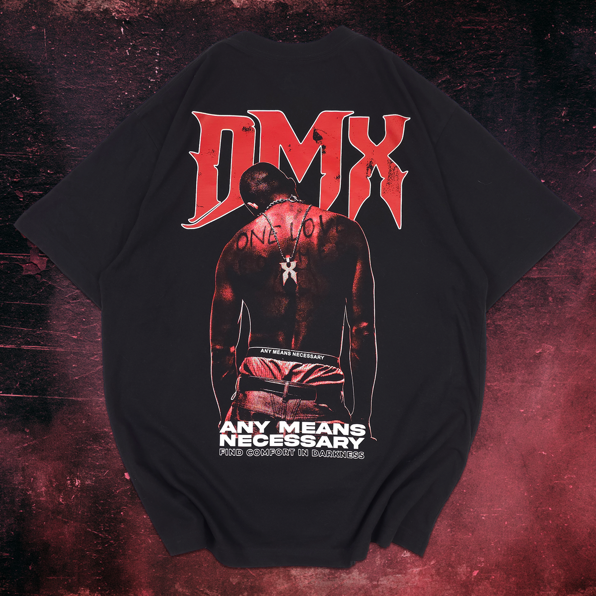 A black short-sleeve graphic t-shirt laid flat against a dark, textured red and black background. The back of the shirt features a large red 'DMX' logo above an illustration of a shirtless man with 'ONE TO ONE' written on his back, and the text 'ANY MEANS NECESSARY' in white below.