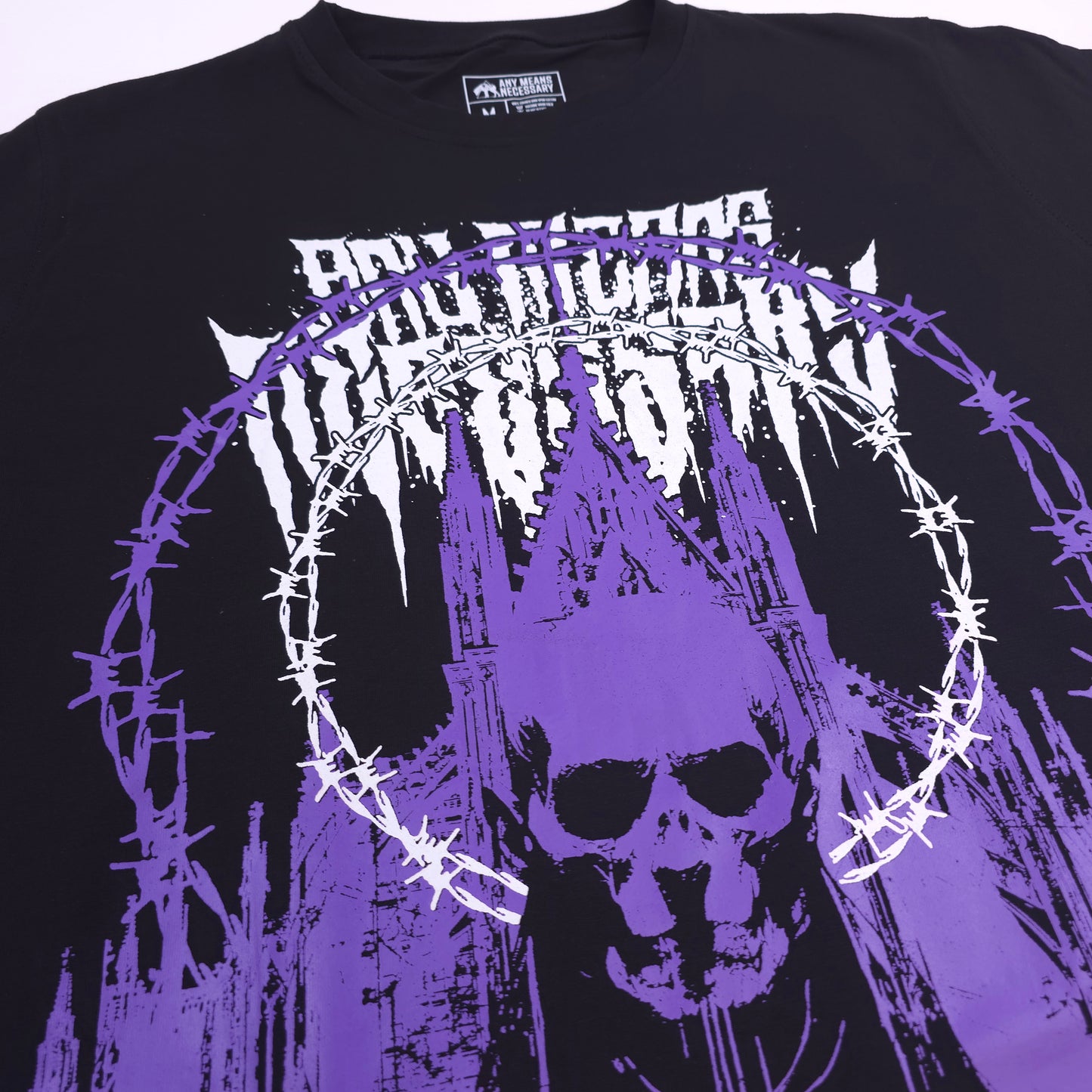 
                  
                    any means necessary shawn coss cathedral t shirt black and purple close up 
                  
                