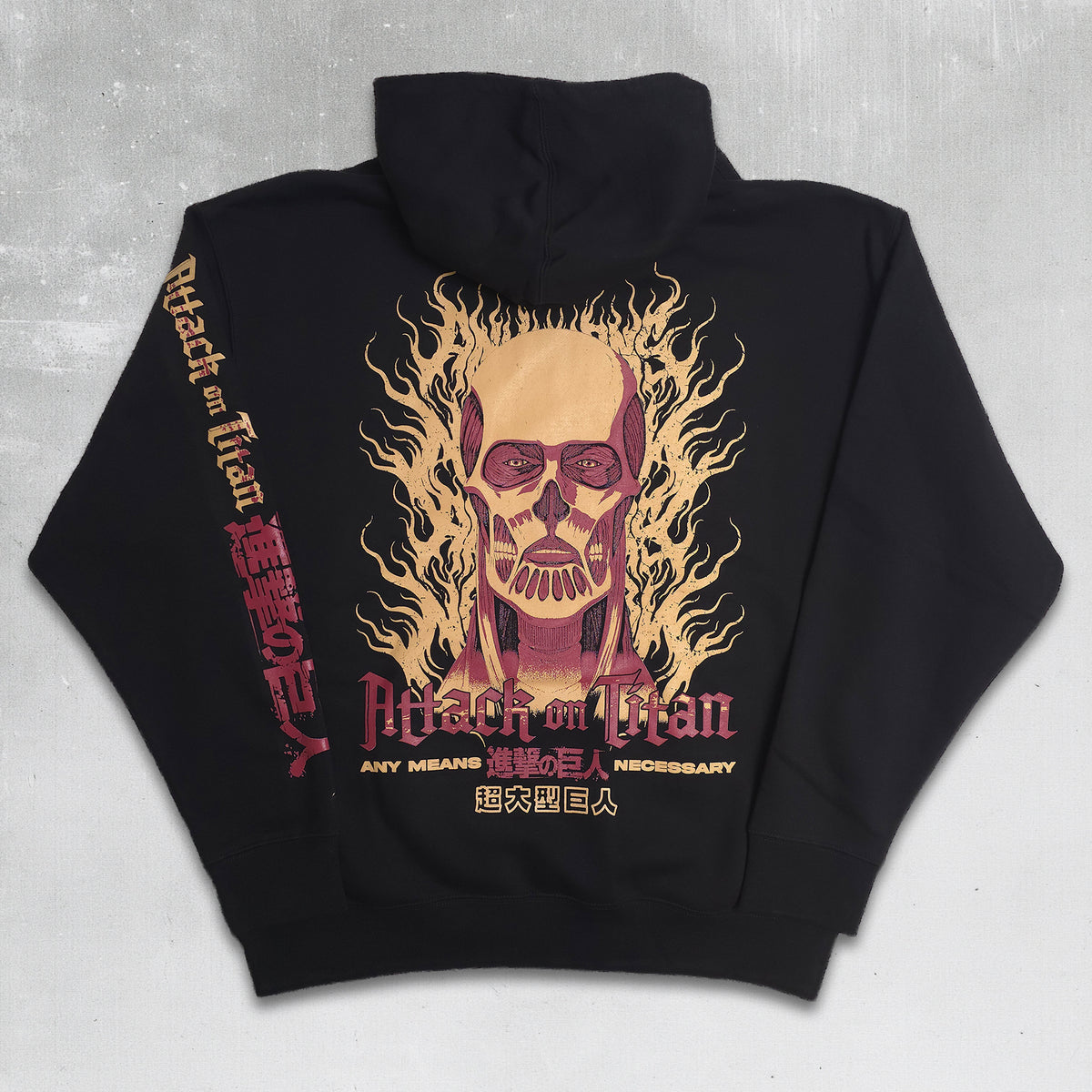 Black pullover hoodie laid flat on a light gray textured background, featuring a large Attack on Titan graphic on the back with a flaming skull illustration and red Japanese text down the left sleeve.