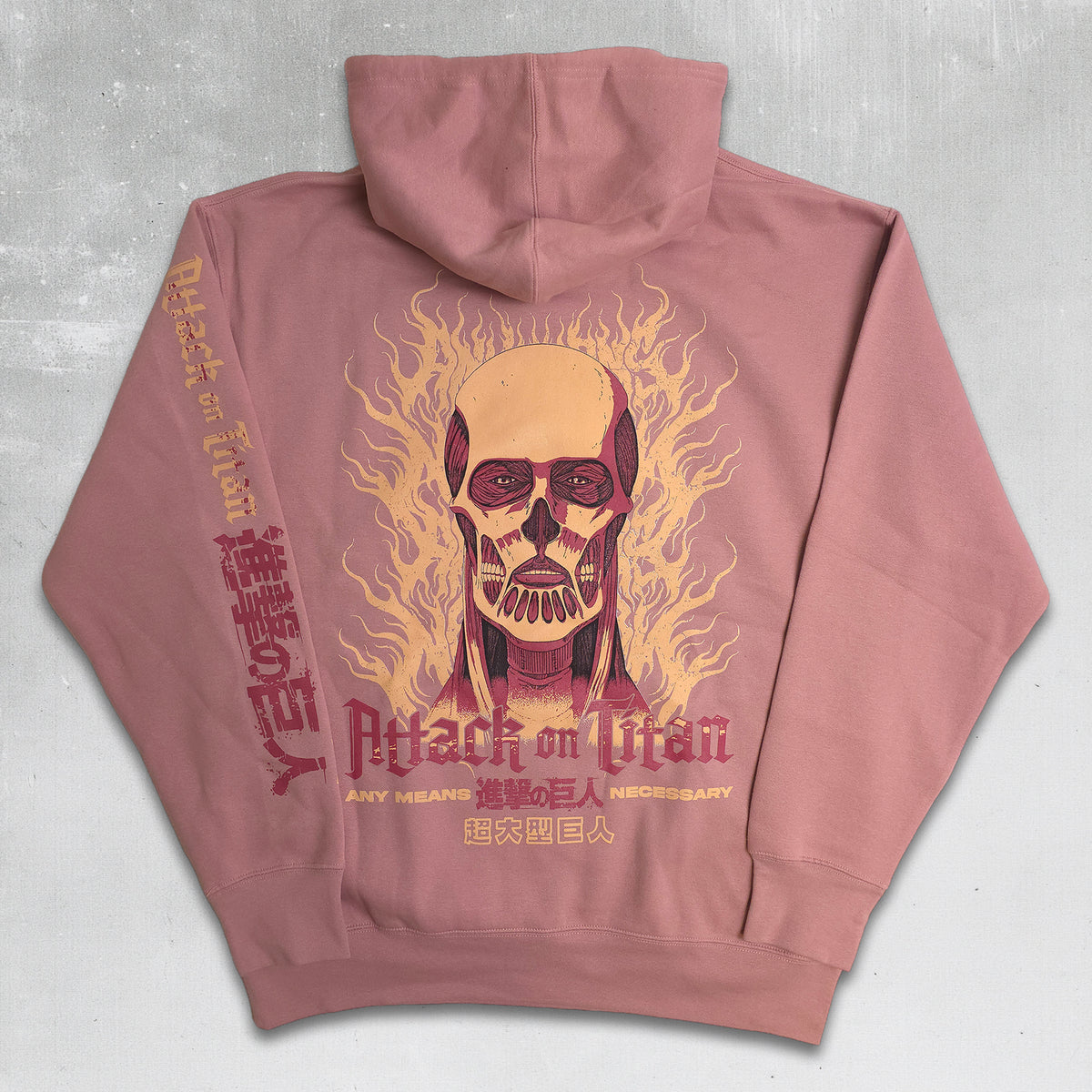 A dusty pink zip-up hoodie shown from the back, featuring a large graphic of a Titan skull surrounded by flames, with 'Attack on Titan' text printed in red and gold.