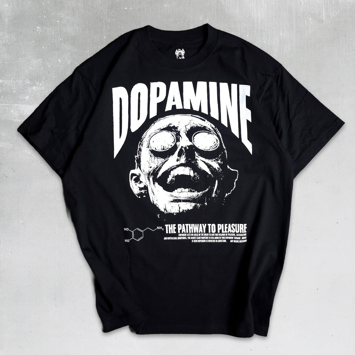 A black short-sleeve graphic t-shirt laid flat on a textured gray background. The shirt features a large white graphic print of a screaming face with the word 'DOPAMINE' above it and 'THE PATHWAY TO PLEASURE' below it.