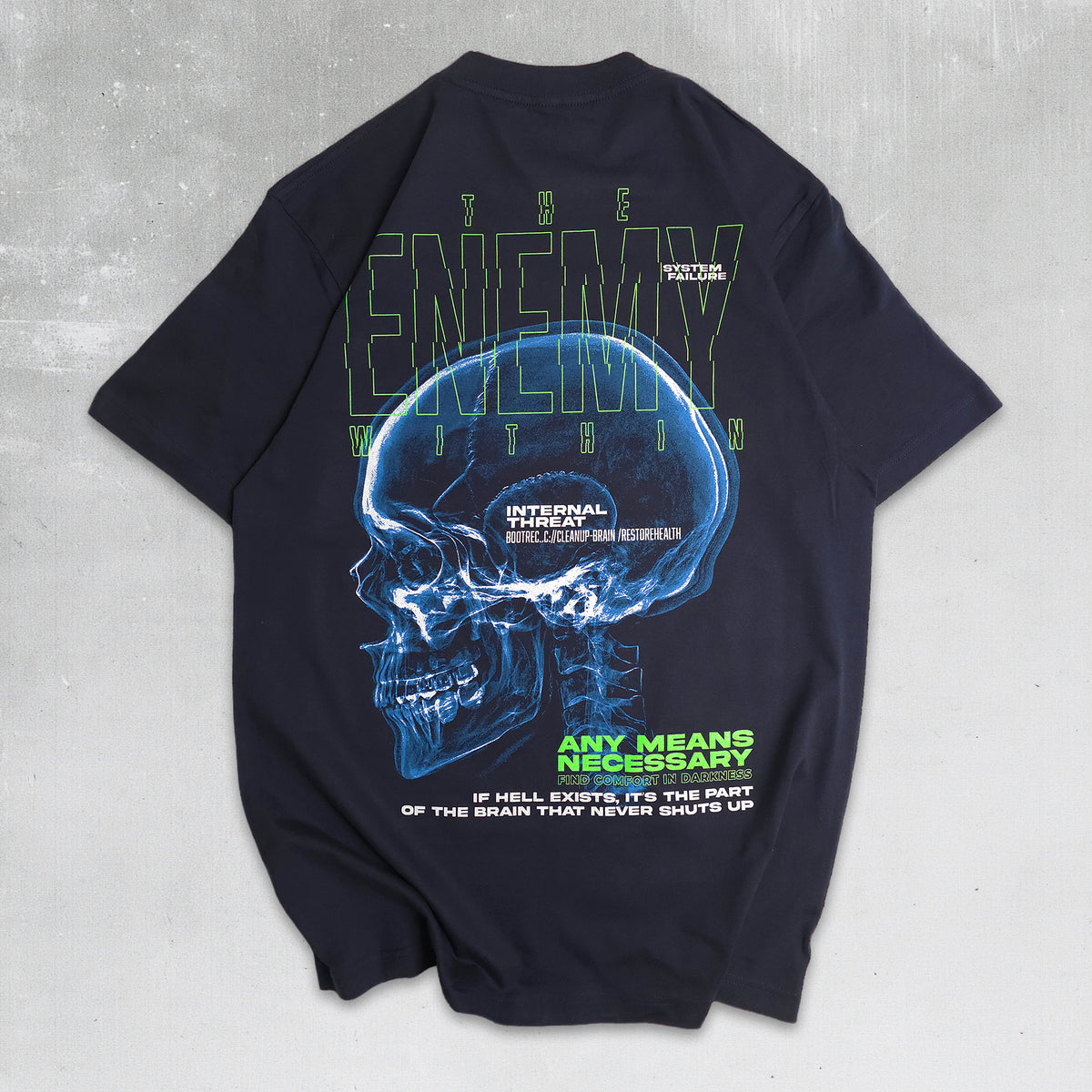 A black short-sleeve t-shirt laid flat on a textured gray background, showing the back graphic. The design features a glowing blue X-ray style human skull with the words 'INTERNAL FREEDOM' and 'THE ENEMY WITHIN' in green and white text.
