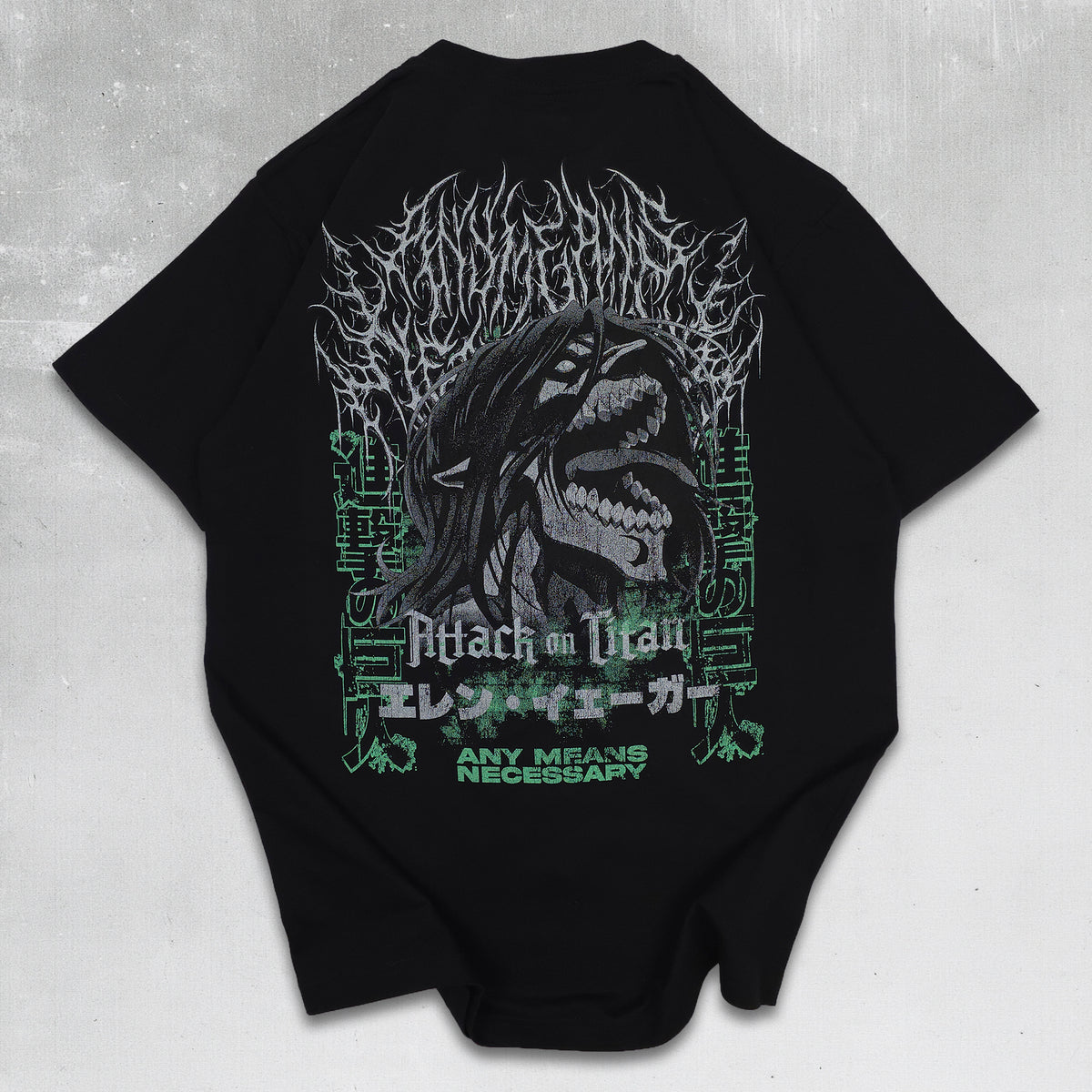 A black short-sleeve T-shirt laid flat on a light gray textured background, featuring a large Attack on Titan graphic print on the back with a screaming titan, white gothic text, and green accents.
