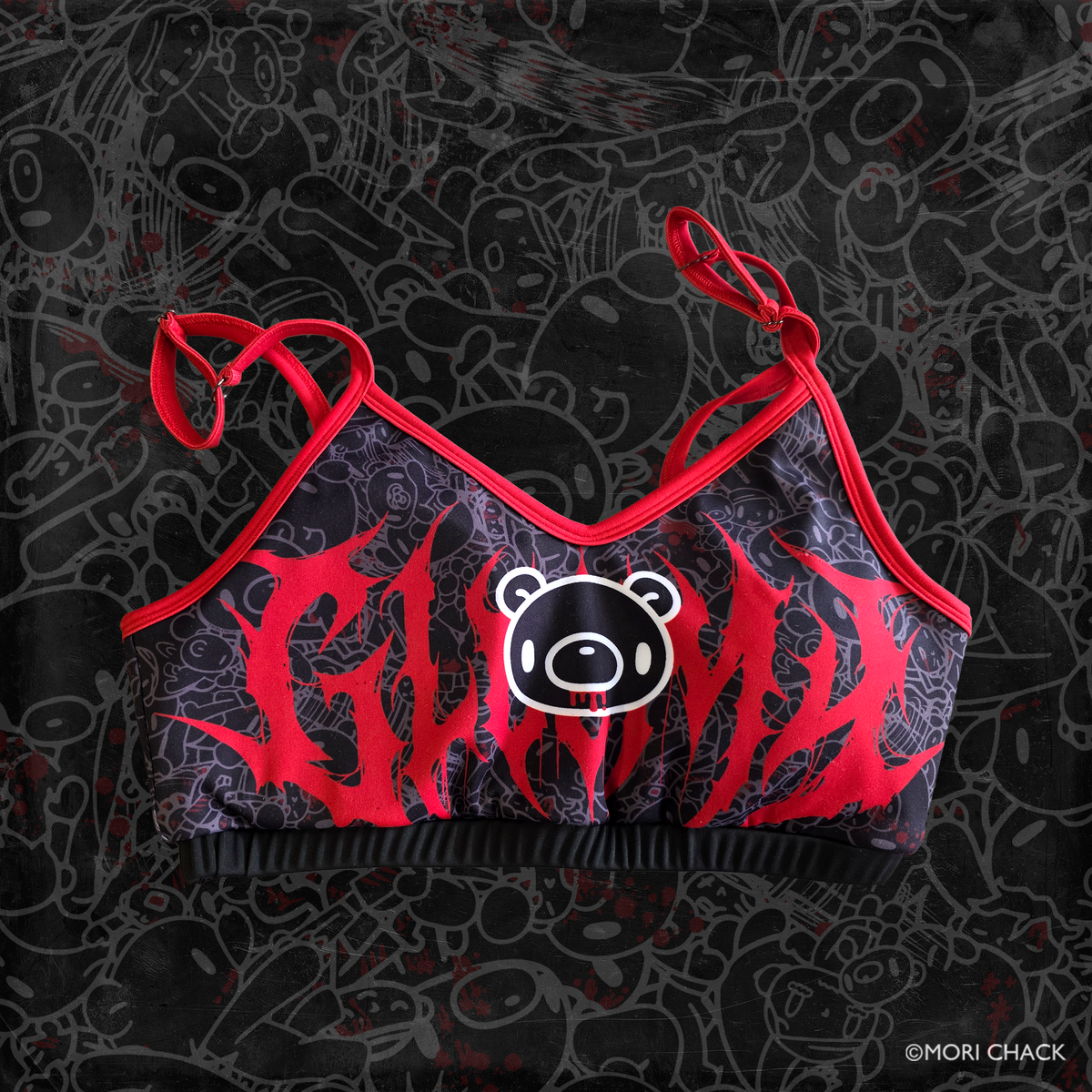 A black and red graphic sports bra featuring a central bear face patch and red spiky lettering, displayed against a black patterned background. gloomy