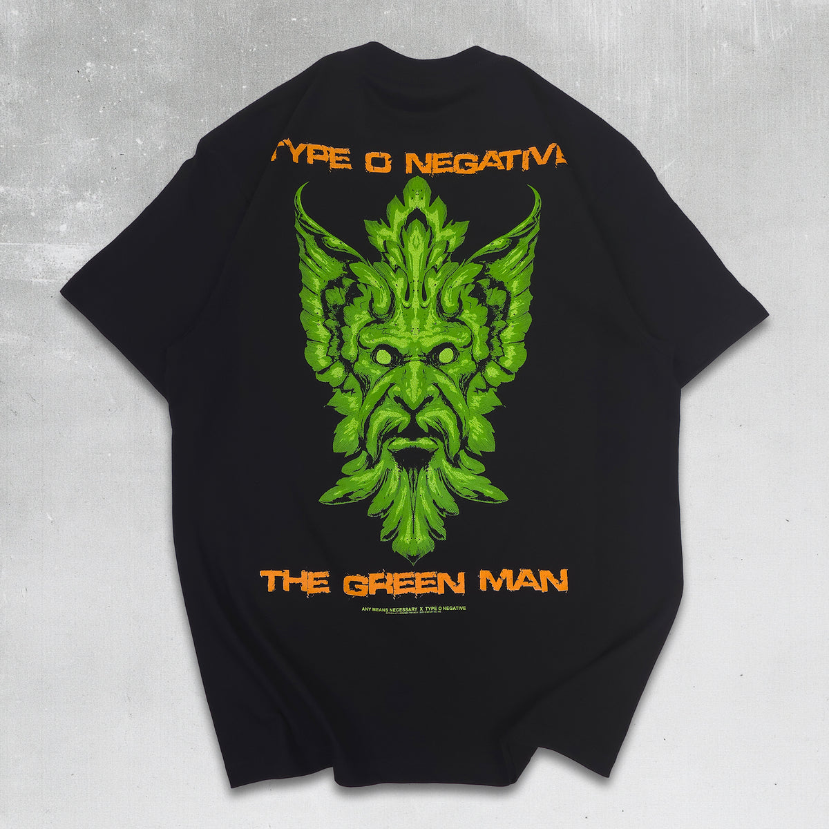 A black short-sleeve T-shirt shown from the back, featuring a large green illustrated face graphic with the words 'TYPE O NEGATIVE' above and 'THE GREEN MAN' below in orange. The shirt is centered on a dark green textured background with thorny branches around the edges.