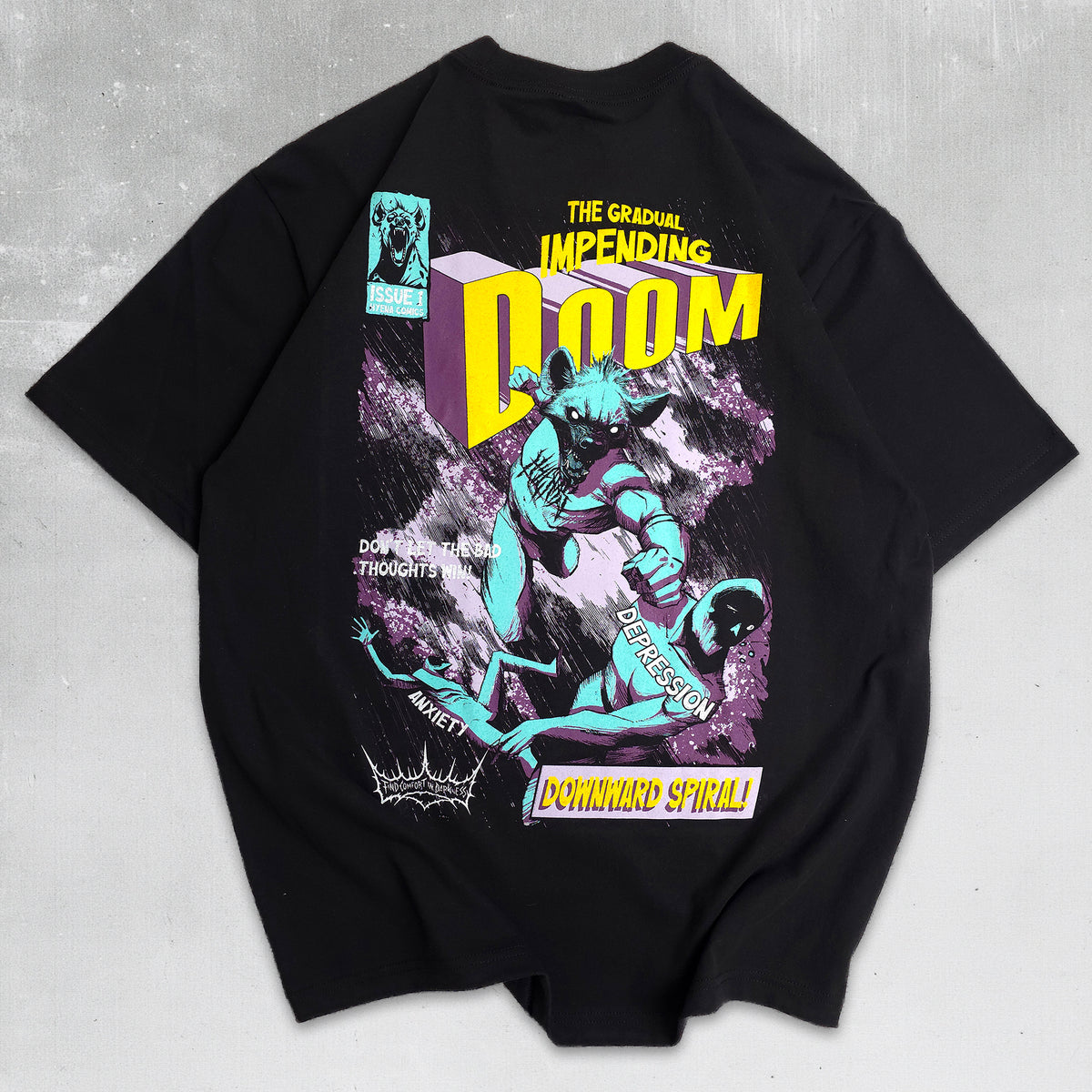 A black short-sleeve graphic t-shirt laid flat on a textured gray background. The shirt features a large, colorful retro comic-style print on the front with the text 'THE GRANDMA'S IMPENDING DOOM' and 'DOWNWARD SPIRAL!'.
