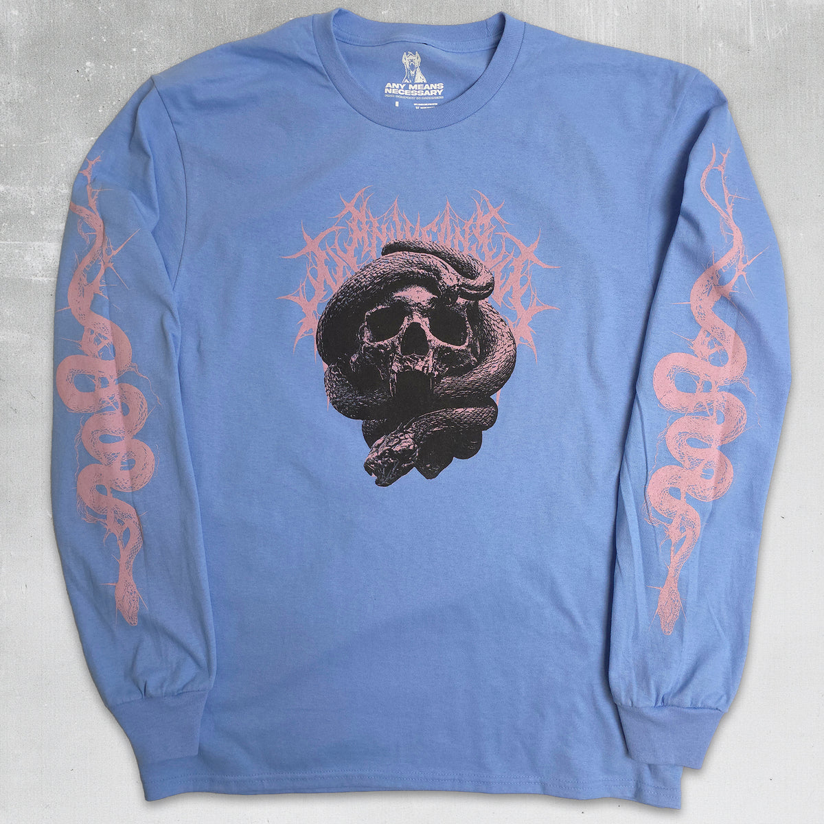 A light blue long-sleeve t-shirt featuring a black skull and snake graphic on the chest, with pink flame-like lettering behind it and pink snake graphics printed down both sleeves, laid flat on a gray textured background.