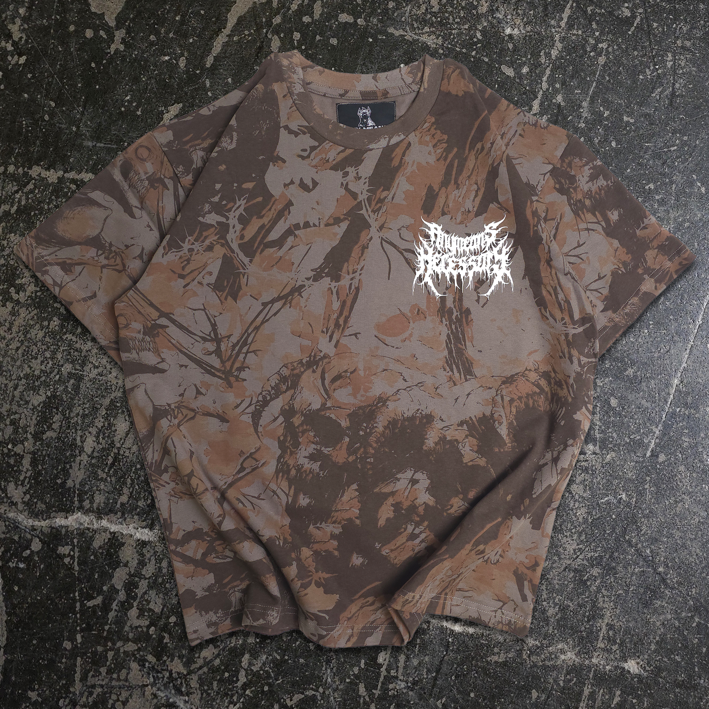 Camouflage-patterned t-shirt with a logo on a textured surface any means necessary shawn coss find comfort from the mud mayhem camo t shirt front
