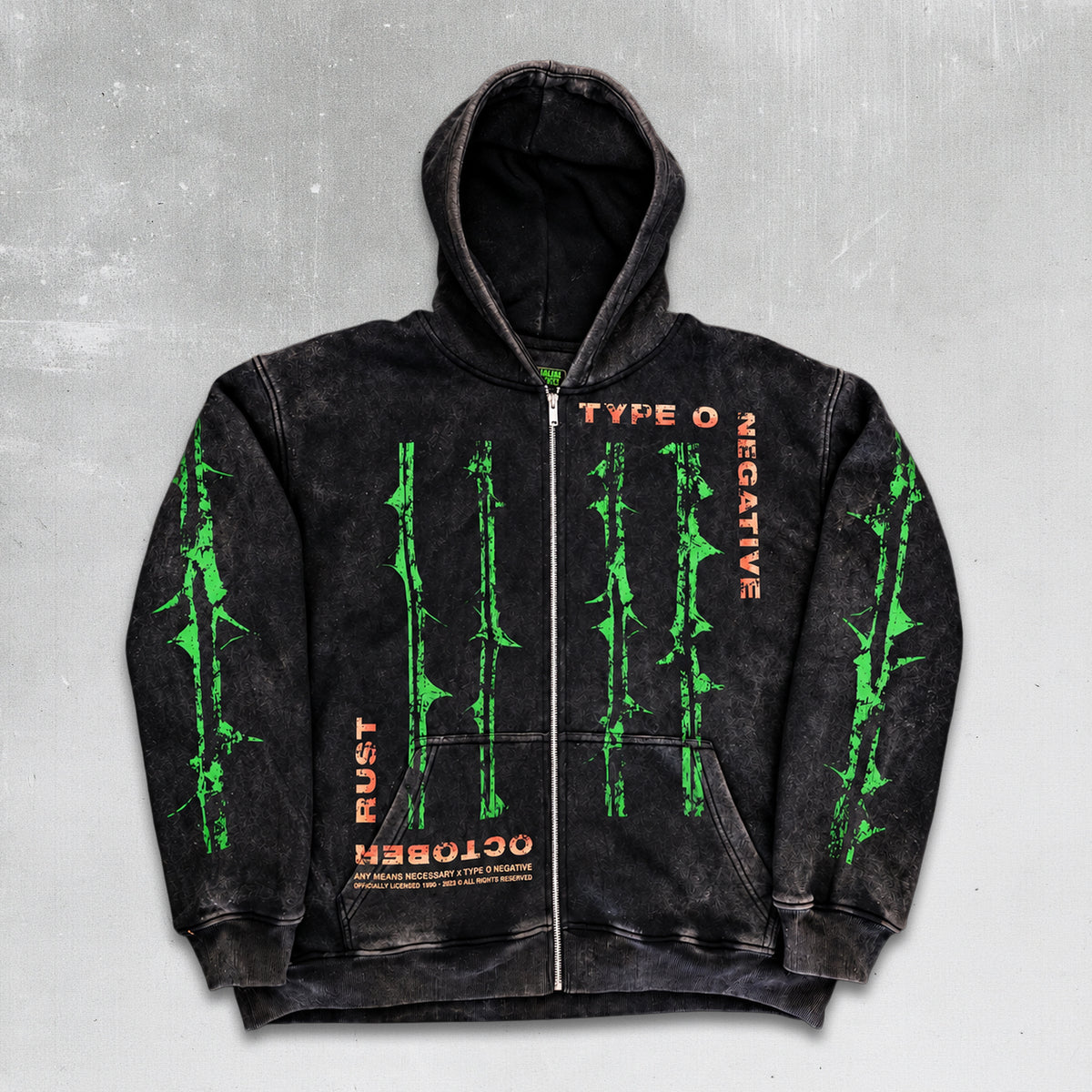 A black acid-wash zip-up hoodie with green barbed wire graphics and orange text, displayed against a dark green background with thorny branches. October Rust Zip Up Type O Negative officially licensed Any means Necessary